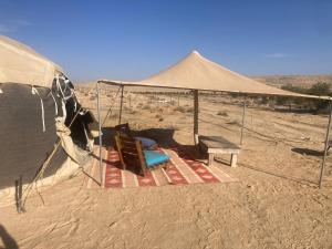 a tent in the desert with a chair and a table at Skyline eco-camp in Mitzpe Ramon