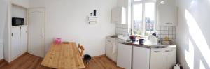 a white kitchen with a wooden table in it at Le petit Château Avesnois - studio pour 1 personne - Cuisine Partagée in Avesnes-sur-Helpe