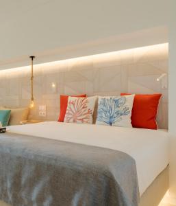 a bedroom with a large white bed with colorful pillows at Pestana Delfim All Inclusive Hotel in Alvor