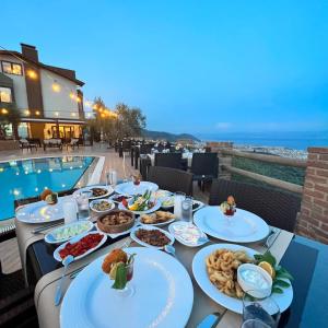 a table with plates of food next to a pool at KAZDAĞLARI ZEYTUNİHAN BUTİK OTEL in Edremit