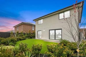 a large white house with a green yard at Brand New Modern 4 Bedroom Luxury Retreat in Caroline Springs