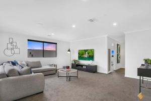a living room with a couch and a table at Brand New Modern 4 Bedroom Luxury Retreat in Caroline Springs