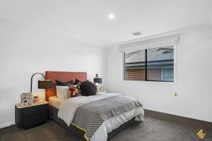 a white bedroom with a bed and a window at Brand New Modern 4 Bedroom Luxury Retreat in Caroline Springs