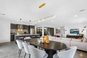 a dining room and living room with a table and chairs at Brand New Modern 4 Bedroom Luxury Retreat in Caroline Springs