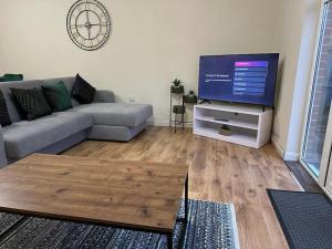 uma sala de estar com um sofá e uma televisão de ecrã plano em Bilborough House - Comfy furnitures, Free Wifi and Free Parking em Swindon