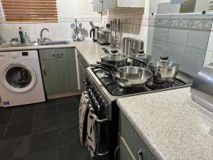 a kitchen with a stove with pots and pans on it at Bilborough House - Comfy furnitures, Free Wifi and Free Parking in Swindon