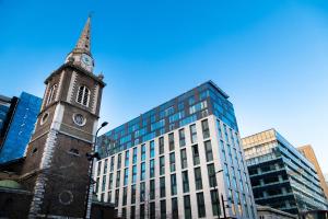 una vecchia torre dell'orologio di fronte a un edificio alto di Hotel Saint London a Londra