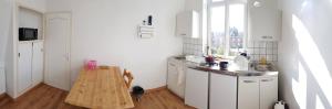 a white kitchen with a wooden table in it at Studio - TV - WIFI - Salle De Bain privée in Avesnes-sur-Helpe