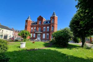 a large red brick building on a green lawn at Studio - TV - WIFI - Salle De Bain privée in Avesnes-sur-Helpe