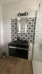 ein Bad mit einem schwarzen Waschbecken und einem Spiegel in der Unterkunft Le Ch’ti Breizh home in Cléguer