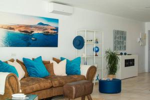 a living room with a brown couch and blue pillows at FRONTLINE VILLA 25, Modern Coastal Design with Amazing Views in Puerto Calero