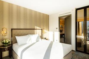 a bedroom with a large white bed and a balcony at Hotel Saint London in London