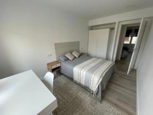 a white bedroom with a bed and a table at Moderno, céntrico. Perfecto para familias. in Vitoria-Gasteiz