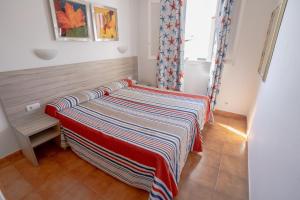 a bed in a room with a striped blanket on it at Seth Sa Mirada in Arenal d'en Castell