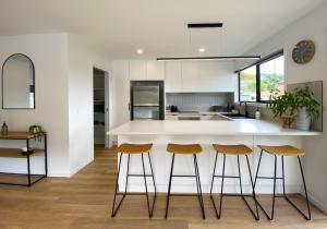 une cuisine avec un comptoir blanc et des tabourets dans l'établissement Albatross Rise - Modern Family Home, à Hobart