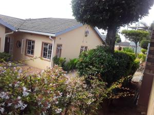 a white house with a tree in front of it at Vuya Nathi Bed and Breakfast in Manzini