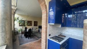 a kitchen with blue cabinets and a living room at Vizi e Virtù in Ferrara