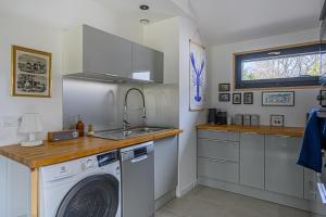 een keuken met een wasmachine en een wastafel bij Les gîtes d'Izel RDC in Ploemel