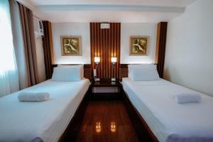 2 camas en una habitación pequeña con sábanas blancas en Emerald Boutique Hotel, en Legazpi