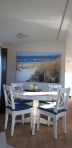 a white dining room table with two chairs and a painting at Chalet Westkapelle op een vakantiepark met 2 slaapkamers 1,7 km van het strand in Westkapelle