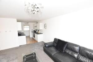 sala de estar con sofá de cuero negro y cocina en 3 Bedroom Apartment in a Quiet Location, en Airdrie