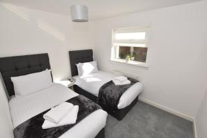 Un dormitorio con dos camas y una ventana. en 3 Bedroom Apartment in a Quiet Location, en Airdrie