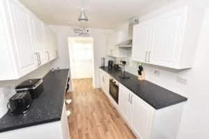 uma cozinha com armários brancos e bancadas pretas em 3 Bedroom Apartment in a Quiet Location em Airdrie