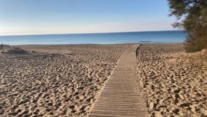 un sentiero in legno su una spiaggia sabbiosa vicino all'oceano di CasaME’ a San Pietro in Bevagna