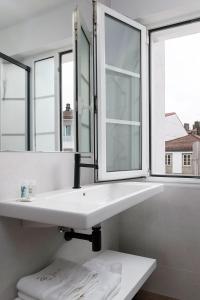 uma casa de banho com um lavatório branco e 2 janelas em PR 25 de Julio em Santiago de Compostela