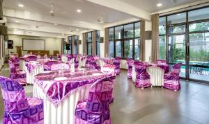 una sala banchetti con tavoli e sedie viola di Fern Tree Resort a Mananthavady