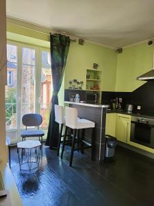a kitchen with green walls and a table and chairs at STUDIO DE L'HORLOGE in Dinan