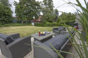 a patio with wicker chairs and a table in a yard at Ferienwohnung Rudi s Huus, FeWo Vermittlung Nordsee in Langendamm