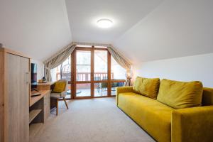 a living room with a yellow couch and a desk at Pensiunea Comfort in Sovata