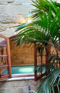 a pool with a palm tree next to a building at Il Mithna farmhouse with indoor heated jacuzzi pool in Għarb