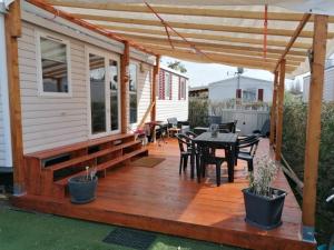 a wooden deck with a dining table and a pergola at Frejus tout confort, maxi 420 m des piscines, climatisation,plus ventilation toutes les chambres, linge de lit et de toilette , coffre fort, lavé vaisselle machine à laver grande terrasse couverte velos et wifi possible in Fréjus