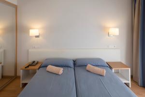 a bedroom with a blue bed with two pillows on it at Seth Playa Azul in Cala en Porter