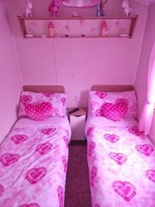 een slaapkamer met twee bedden met roze harten erop bij 3 bedroom Caravan Craigtara in Ayr