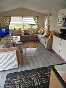 a living room with a couch and a table at 3 bedroom Caravan Craigtara in Ayr