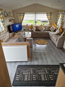 a living room with a couch and a tv at 3 bedroom Caravan Craigtara in Ayr