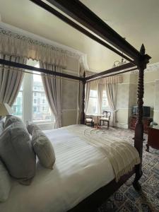 sypialnia z dużym łóżkiem z baldachimem i białymi poduszkami w obiekcie Montclare w mieście Llandudno