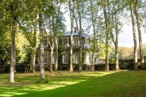 uma casa antiga rodeada de árvores num campo em Le Domaine de Courances - Pierres d'Histoire em Courances