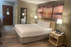 um quarto de hotel com uma cama e uma mesa de cabeceira com uma cama sidx sidx sidx em Days Inn by Wyndham Seatac Airport em SeaTac