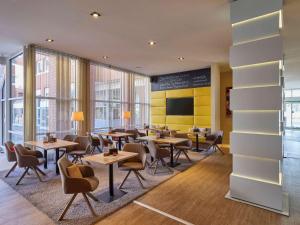 uma sala de jantar com mesas, cadeiras e janelas em Mercure Hotel Severinshof Köln City em Colônia