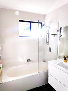 Un baño blanco con bañera y lavabo. en Lovely Queen Room + TV +Wifi FREE Parking Pet Friendly, en Glenfield