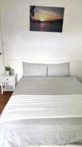 Un dormitorio con una cama blanca con un cuadro en la pared. en Lovely Queen Room + TV +Wifi FREE Parking Pet Friendly, en Glenfield