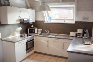 eine Küche mit weißen Schränken, einem Waschbecken und einem Fenster in der Unterkunft OH 42 - Strandvogt Komfort in Dorum Neufeld