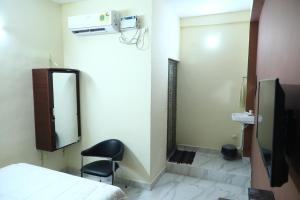 a room with a bed and a chair and a mirror at Babu Naidu Residency in Vellore