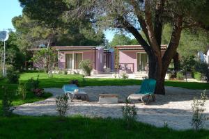 a pink house with two chairs and a tree at Apartments Erica Lux in Novigrad Istria