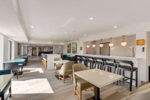 a restaurant with tables and chairs and a bar at La Quinta by Wyndham Des Moines West Clive in Clive