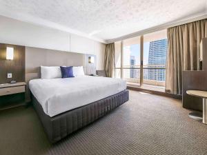 a hotel room with a large bed and a large window at Novotel Surfers Paradise in Gold Coast